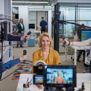 ciphr brand ad behind the scenes image. woman in centre with hands around her holding telephones